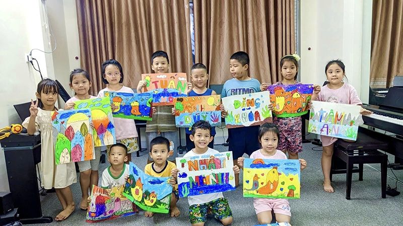 Học viên lớp mỹ thuật IRIS giơ các bức tranh nhiều màu