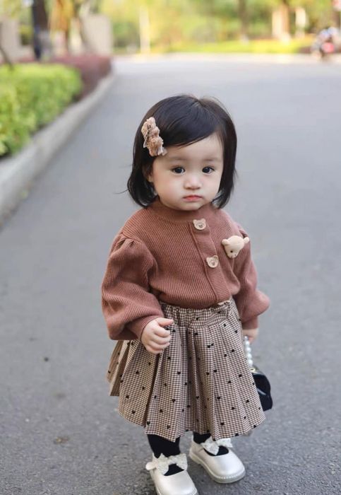 Bé gái mặc áo len nâu và chân váy kẻ, ảnh của Thanh Hằng Baby